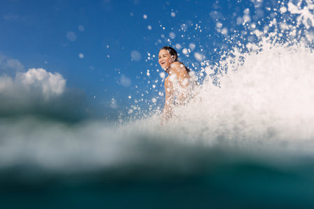 Female surfer on surfboard during surfing. Smiling surfer woman and ocean waveの写真素材