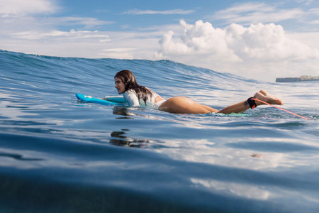 Surf girl floating on surfboard. Attractive surfer woman in ocean during surfing