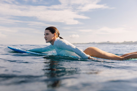 Surf girl floats on surfboard. Attractive woman in ocean during surfing. Surfer and ocean