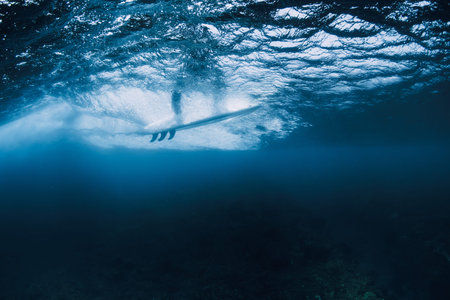 Underwater view of surfer riding wave with surfboardの写真素材