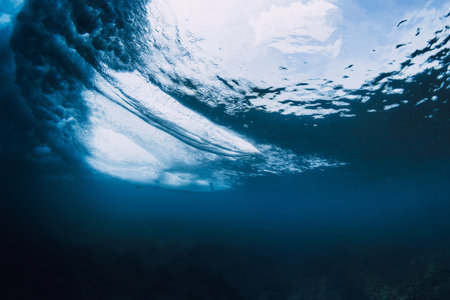 Underwater view of surfer riding with surfboard, breaking ocean waveの写真素材