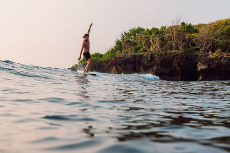 Active surfer carving a wave near rocky shoreの写真素材