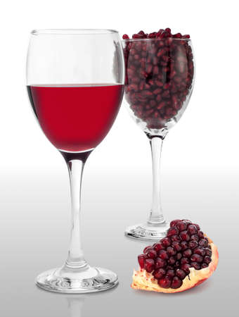 Two glasses of pomegranate juice and seed, with fruit segment beside.の写真素材
