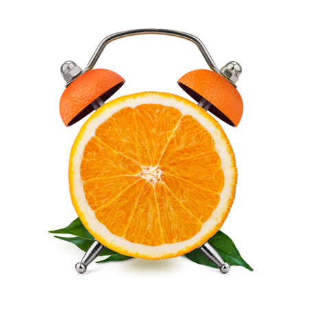Cut orange, with leaves, as an alarm clock on a white background. Healthy time concept.の写真素材