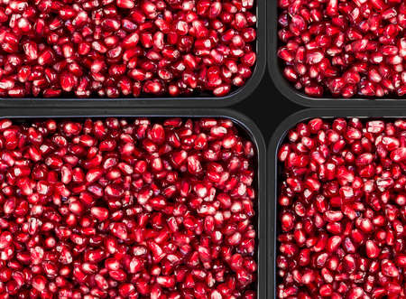Texture of red ripe pomegranate seeds with edges of black boxes.の写真素材