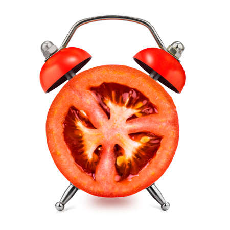 Cut Tomato as an alarm clock on a white background. Healthy time concept.の写真素材