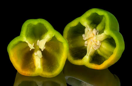 A Green Bell Pepper, cut in half, isolated on black reflective background.の写真素材