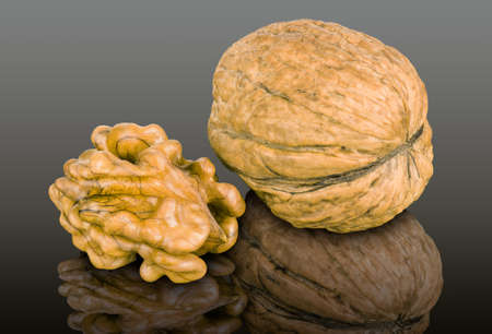 A walnut kernel and a whole walnut, isolated on black reflective background.の写真素材