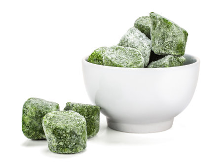 Frozen spinach blocks in a white bowl, on a white background. Spinach (Spinacia oleracea) is a leafy green vegetable, loaded with nutrients and antioxidants.の写真素材