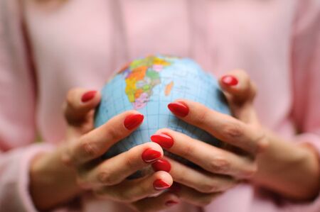 Female hands with a small globe with Ukrainian names and Cyrillic letters on it. African continent and Indian Ocean are visible. Human responsibility concept.の写真素材