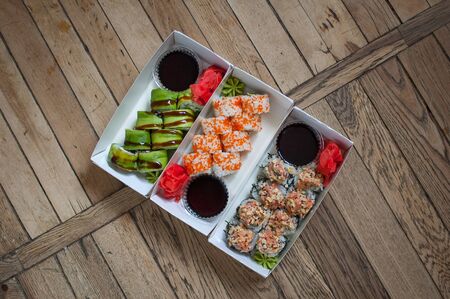 Japanese cuisine. Sushi set on a tree carton box over wooden background. Food for take away or sushi delivery conceptの写真素材