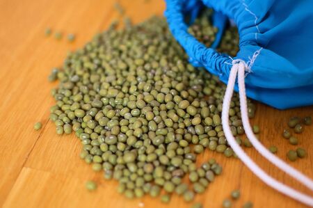 Close up of green mung bean vigna radiata in blue reusable package on wooden background. Eco packaging conceptの写真素材