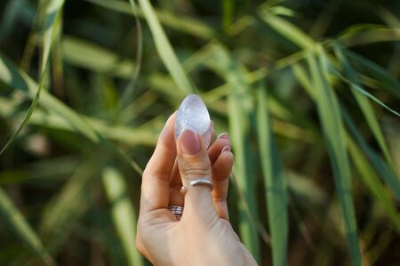 Female hand with french manicure holding transparent violet amethyst yoni egg for vumfit, imbuilding...