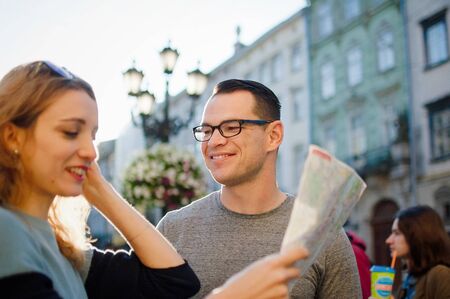 Young couple watching the city map and searching for direction early in the morning on empty ancient square somewhere in Europeの写真素材