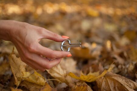 Outdoors photo of traditional hutsul drymba, jaws harp, silver vargan in female hand on fallen leaves background during autumn dayの写真素材