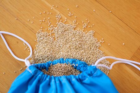 White quinoa seeds in transparent blue reusable bag on wooden background. Vegetarian food conceptの写真素材