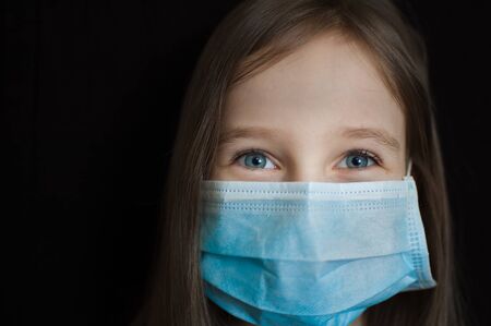 Coronavirus Covid-19 outbreak. Little girl is looking at the camera with hope. Stay positive concept during self-isolation at home wearing personal protective maskの写真素材