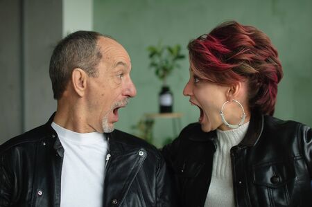 Emotional family portrait of adult daughter and senior father in loft room with houseplants....