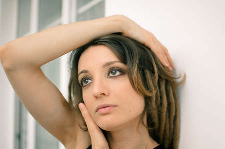 Indoors female portrait of a sensual girl with long dreadlocks and dark makeup with black eyeshadow,...