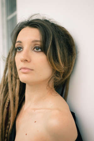 Indoors female portrait of a sensual girl with long dreadlocks and dark makeup with black eyeshadow,...