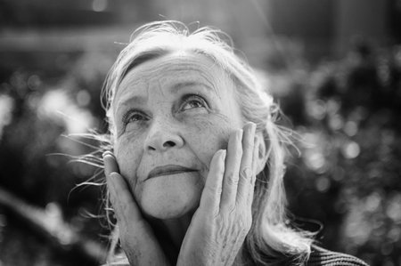 Black and white portrait of senior woman with grey hair and face with wrinkles outdoors relaxing at the parkの写真素材