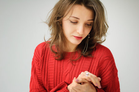 Studio portrait of young woman in red knitted sweater and earring on white background