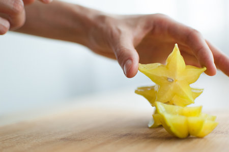 Female hands are holding slice of exotic ripe starfruit or averrhoa carambola. Healthy food, fresh organic star apple fruitの写真素材