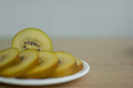 Slices of golden kiwi with yellow pulp on white plate on the kitchen. Exotic fruits, healthy eating conceptの写真素材