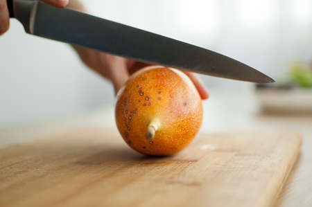 Fresh organic ripe granadilla or yellow passion fruit cut in half on a wooden board. Exotic fruits, healthy eating conceptの写真素材