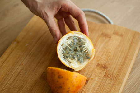 Fresh organic ripe granadilla or yellow passion fruit cut in half on a wooden board. Exotic fruits,...