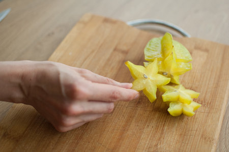 Female hands are holding slice of exotic ripe starfruit or averrhoa carambola. Healthy food, fresh organic star apple fruitの写真素材