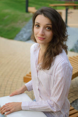 Female portrait of young woman with silver laptop, businesswoman is posing with digital tablet...