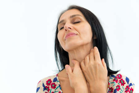 Studio photo of middle aged woman starting getting grey-haired wearing dress with flowers on white background, middle age sexy lady, cosmetology conceptの写真素材