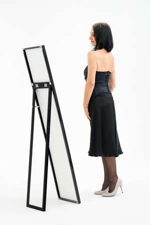 Studio portrait of middle aged woman starting getting grey-haired wearing black clothes on white background, middle age sexy lady, cosmetology conceptの写真素材