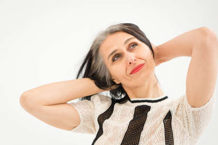 Studio photo of middle aged woman starting getting grey-haired wearing black and white clothes on white background, middle age sexy lady, happy life conceptの写真素材