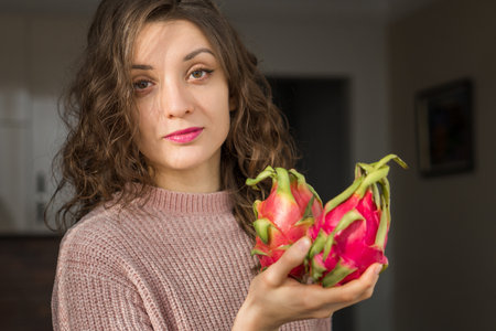 Young girl is holding two fresh ripe organic dragon fruits or pitaya, pitahaya. Exotic fruits, healthy eating conceptの写真素材