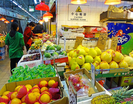 North Point, Hong Kong - February 13, 2016: Booth with fresh fruits and vegetables on the Java Road Market in North Point, Hong Kong. Customers are at the booth and buy food.のeditorial素材