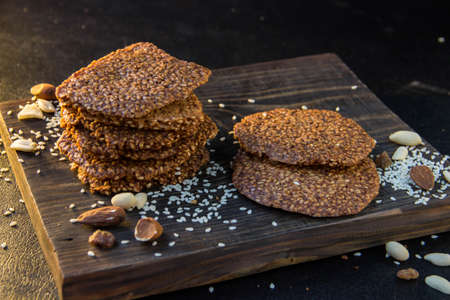 homemade biscuits with sesame seeds and nuts on a black background