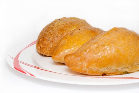 Baked pies on a white plate with red drawingの写真素材