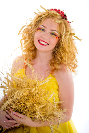Beautiful girl dressed yellow with wheaten ears. Red-haired girl with freckles in an image of hot summer.の写真素材