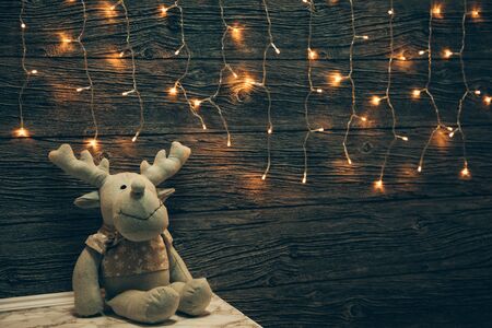 Garland Lights, toy deer on old grunge wooden board. Christmas and New Year decoration.  Christmas lighting on wooden planksの写真素材