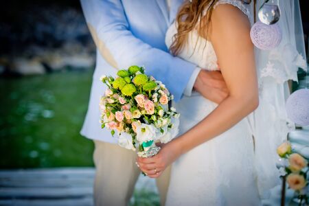 Wedding photo with two newlyweds near the river. The women has a wedding bouquet of flowers.の写真素材