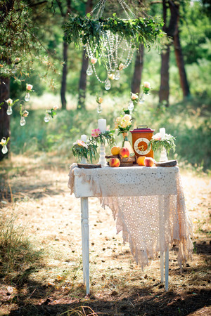 Wedding decor for photographing with the bracket clock, flowers, candles and peaches on a ancient suitcase. Roses in bulbs on a background . Decoration of a wedding photoshoot.  Details of a wedding decor.の写真素材