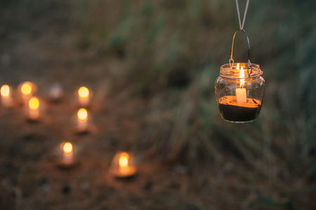 The lamp made of a jar with a candle  is  hanging  on a tree at night. Wedding night decor. Night ceremonyの写真素材