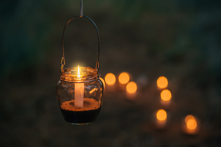 The lamp made of a jar with a candle  is  hanging  on a tree at night. Wedding night decor. Night ceremonyの写真素材