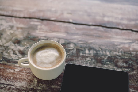 Coffee cup and smart phone on old wooden table background.の写真素材