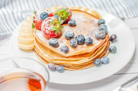 Pancakes with fresh berries and honey for breakfast, selective focus