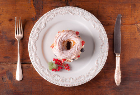 Cake with cream and berries on a white plate on a wooden background
