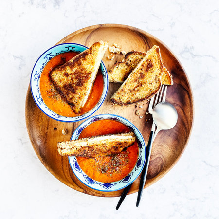 Homemade pumpkin cream soup with toasted bread on white marble backgroundの写真素材