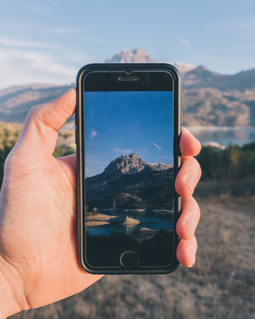 Taking a photo with a smart phone of a mountain lake in Spainの写真素材